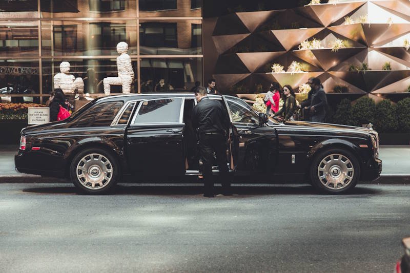 Chauffeur opening the door of a black car for a Billy Bishop Airport pickup in Toronto