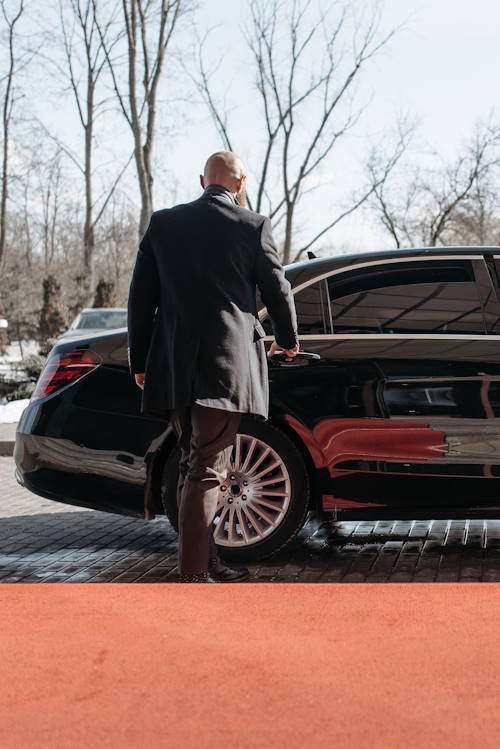 Professional airport chauffeur in Toronto opening the door of a luxury black car